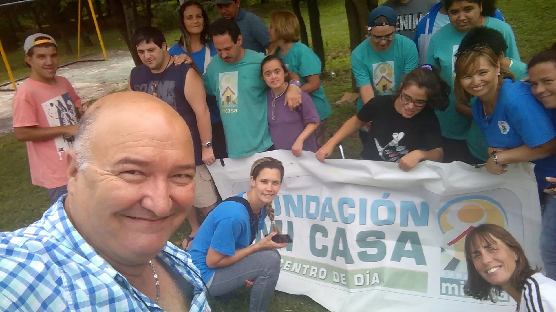 Larry De Clay sacándose una selfie junto a la bandera de la Fundación Mi Casa